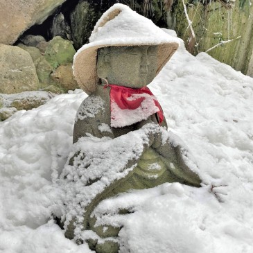 A Buddhist statue sat in prayer on a snow-covered mountainside.